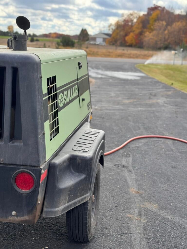 Image Irrigation technician blowing out a residential sprinkler system before a Minnesota freeze